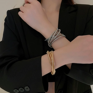 Macro detail of layered stretch bracelets in gold and silver with spiral metal texture