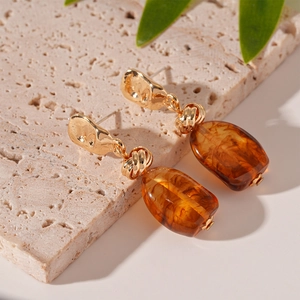 Retro geometric amber acrylic earrings with gold hammered metal details on stone background