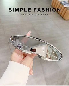 Detail of silver wrap-around Y2K sunglasses with futuristic mirrored lenses being held