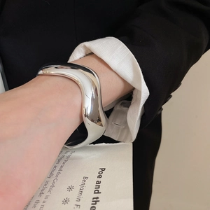 Detailed view of irregular wavy silver open cuff bracelet with polished mirror finish