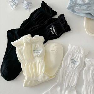 Grey ruffled cotton socks with bow and letter embroidery in a clean flat lay