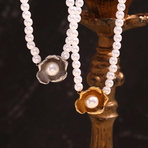 18K gold and silver flower pendant pearl necklaces on a minimalist dark background