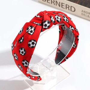 Detail of red knotted headband featuring a classic white and black soccer ball print design