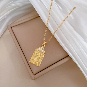 Close-up of gold Virgin Mary portrait pendant with crystal cross and titanium chain