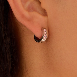 Silver stainless steel hoop earrings with pink zircon stones worn on a model ear