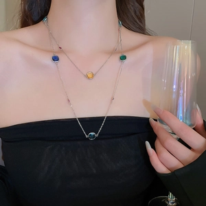 Detail of layered stainless steel necklace with colorful square crystals on a model