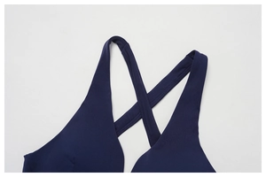 Detailed close-up of navy blue yoga bra featuring criss-cross straps and deep V-neckline
