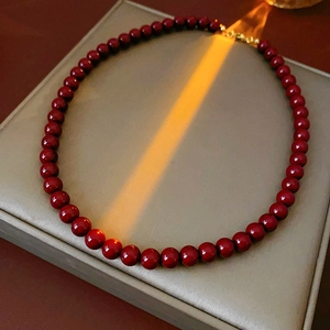 Detailed view of red beaded titanium necklace on grey pad with warm lighting effects