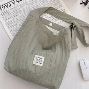 Detail of sage green pleated canvas tote bag with adjustable strap and brand patch