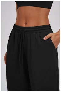Detail of black baggy sweatpants showing the elastic drawstring waist and side pocket texture