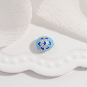 Détail macro d'une perle fleur en émail cloisonné bleu sur un plateau blanc ondulé