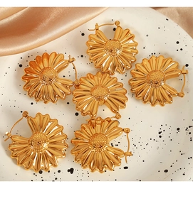 Detailed shot of 18K gold plated hollow sunflower earrings on white ceramic tray