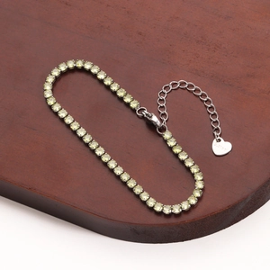 Detail of light green tennis bracelet with stainless steel heart charm and adjustable chain