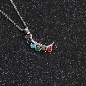 Detail of silver crescent moon pendant with seven colorful chakra stones on a cord chain