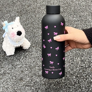 Vue détaillée d'une bouteille d'eau noire mate avec motifs de nœuds roses
