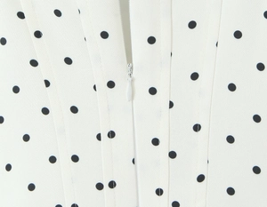 Detail of invisible zipper on French style white polka dot dress with woven fabric texture
