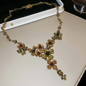 Close-up of vintage flower necklace with brown and green crystals on a beige surface