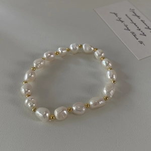 Armband aus unregelmäßigen Barock-Süßwasserperlen mit goldenen Perlen auf hellem Grund