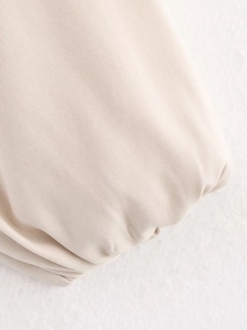 Macro shot of beige twill fabric texture and pleated hem details on the baseball jacket