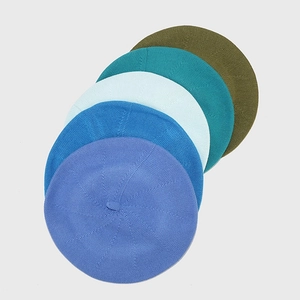 Stacked set of five knitted cotton berets in shades of blue, green and olive green