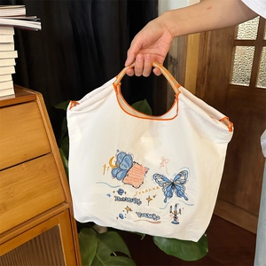 Detail der gestickten Schmetterlinge und Kunstschrift auf einer weißen Segeltuchtasche