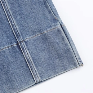 Gros plan détaillé de l'ourlet à double surpiqûre sur un jean évasé en denim bleu sergé