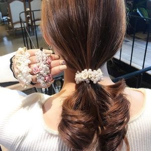 Detailed view of elastic hair tie with silk rose and faux pearl on elegant ponytail