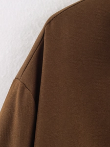 Vue macro de la veste en sergé marron foncé montrant la couture et la texture du tissu