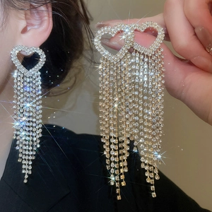 Close-up of sparkling heart tassel earrings with dangling rhinestones on a female model