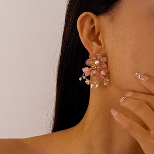 Close-up of elegant pink floral drop earrings with glass petals and dangling pearls