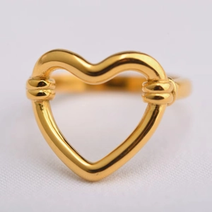 Macro d'une bague coeur plaquée or 18 carats avec motif nœud sur tissu blanc