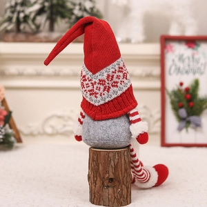 Christmas gnome doll with red knitted hat and long legs on a rustic wooden base