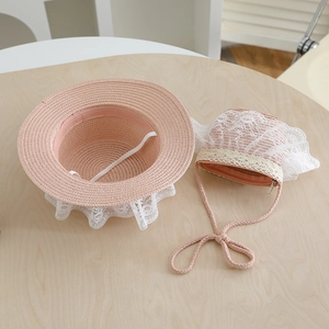 Detailed view of pink straw hat and lace purse set on light wood background