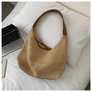 Detailed macro view of woven beige straw hobo bag with dark brown leather strap