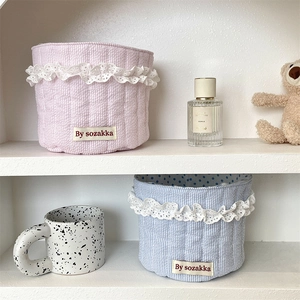 Close-up of pink and blue quilted fabric storage baskets with delicate lace edges