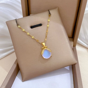 Gold titanium necklace with oval opal bee pendant in jewelry box on soft fabric