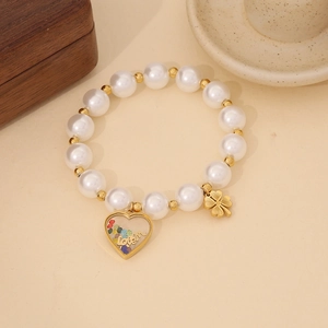 Close-up of white pearls and golden beads with clover and heart love pendants