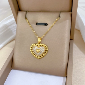Detailed macro view of a heart-shaped gold-plated necklace with crystals in a gift box