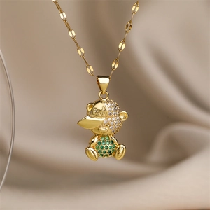 Vue macro du pendentif ourson doré serti de zircons cubiques verts et clairs