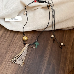 Détail du collier pendentif fleur bohème avec glands et perles sur fond de lin