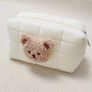 Detail of white quilted plush pencil case with cute brown teddy bear head and zipper