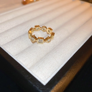 Macro shot of gold plated dragon ring with square and heart zircons on white tray