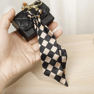 Close-up of black quilted mini purse with checkered silk ribbon and gold clasp