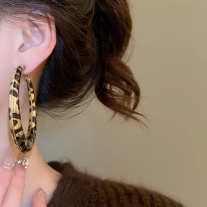Macro shot of large hoop earring featuring vintage leopard print design on a model