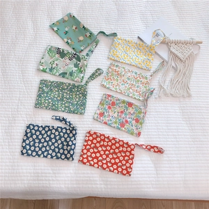 Flat lay of eight colorful floral cotton mini wristlet pouches on a white quilted background