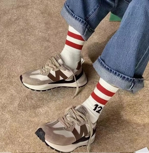 Close-up of retro suede sneakers with brown M logo and vintage number 12 socks