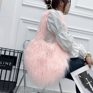 Model showcasing a large pink long-hair faux fur shoulder bag with soft fluffy texture