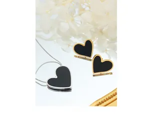Detail shot of heart jewelry set featuring black enamel necklace and matching earrings