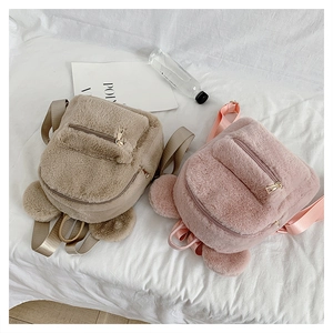 Detailed close-up of khaki and pink plush backpacks with cute bear ears on soft fabric
