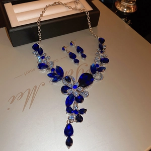 Detail view of sapphire necklace and earrings set with floral motifs in a luxury gift box